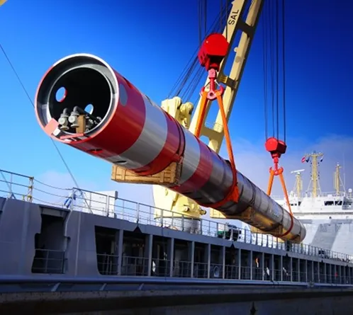 Grúa portuaria izando una pieza industrial cilíndrica de gran porte